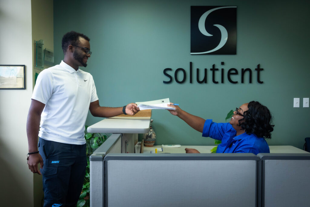 Solutient Employee handing papers to co-worker